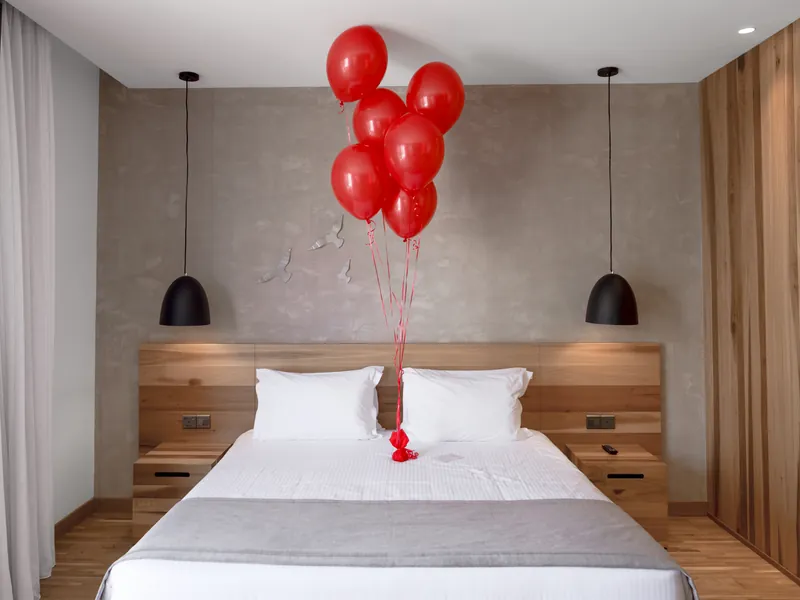 Bouquet of red helium balloons above the bed in an Anemi guest room
