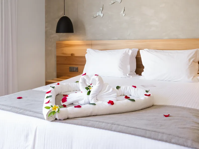 Swan towel arrangement with red rose petals laid on the bed on arrival