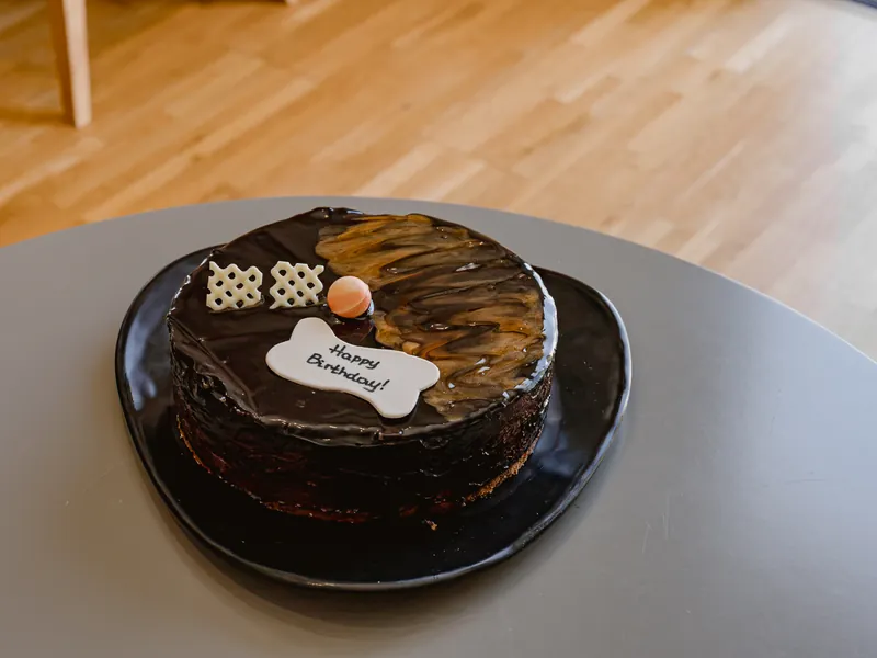 Chocolate birthday cake with a Happy Birthday plaque on a dark serving plate