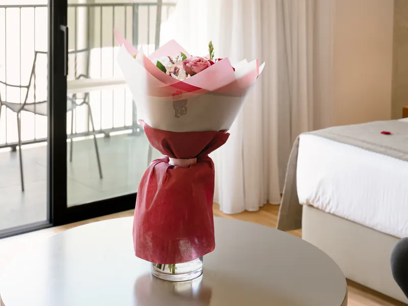Wrapped bouquet of pink roses on the table of an Anemi guest room