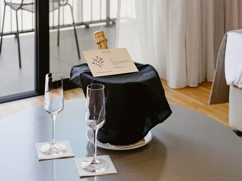 Chilled bottle of sparkling wine in an ice bucket with two flutes on the in-room table